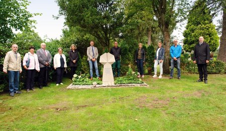 Gruppe Menschen um einen Grabstein