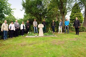 Gruppe Menschen um einen Grabstein