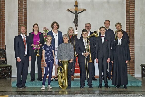 Erwachsene und Jugendliche mit Blechblasinstrumenten mit einer Pastorin in der Kirche - Copyright: Ev.-Luth. Kirchengemeinde Schwarzenbek