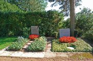 Zwei Gräber mit roten Blumen und Grabsteinen