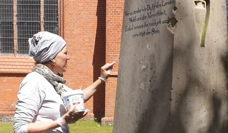 Restauratorin Malaika Krohn an dem Compa-Grabstein