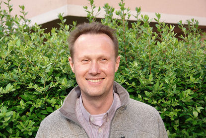 Portraitbild: Pastor Andreas Schöer steht vor einer grünen Hecke - Copyright: Ev.-Luth. Kirchengemeinde Schwarzenbek