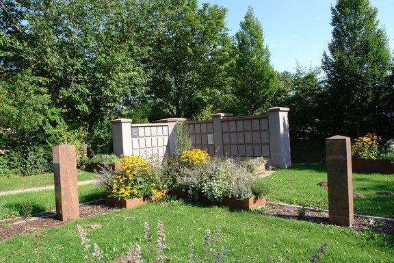 Urnenwand mit zwei Stelen davor auf dem Friedhof