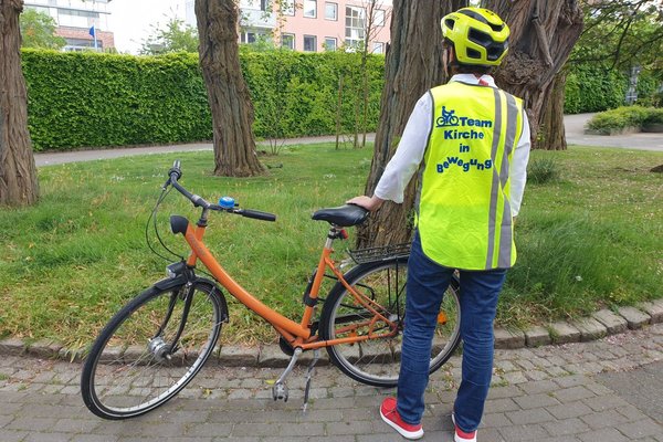 Frau mit Fahrrad trägt gelbe Weste - Copyright: Kirchengemeinde Schwarzenbek